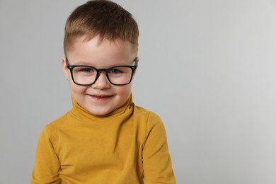 Photo of Cute little boy in glasses on light grey background. Space for text
