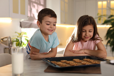 Cute little children with cookies and milk in kitchen. Cooking pastry