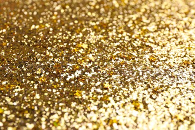 Photo of Shiny bright golden glitter as background, closeup