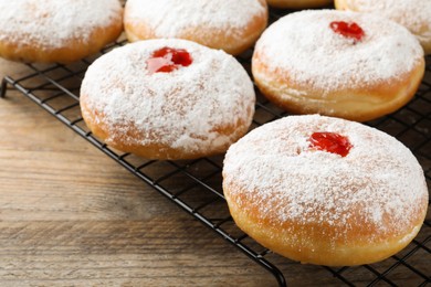 Many delicious donuts with jelly and powdered sugar on wooden table