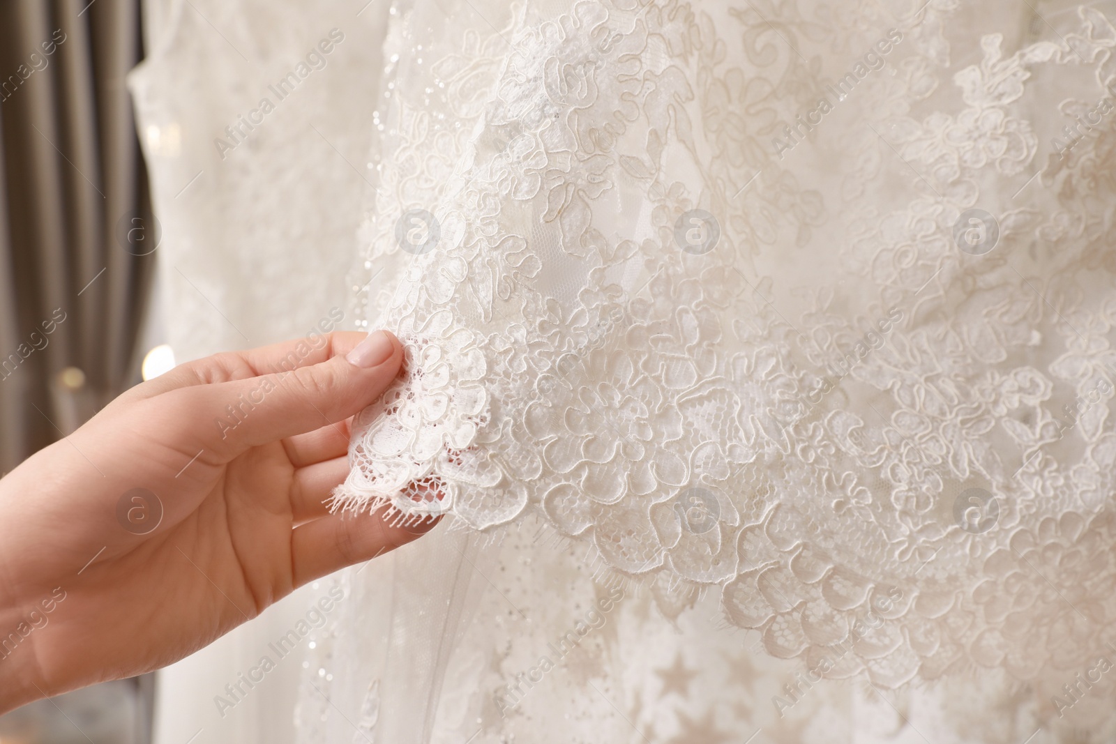 Photo of Young woman choosing wedding dress in salon, closeup