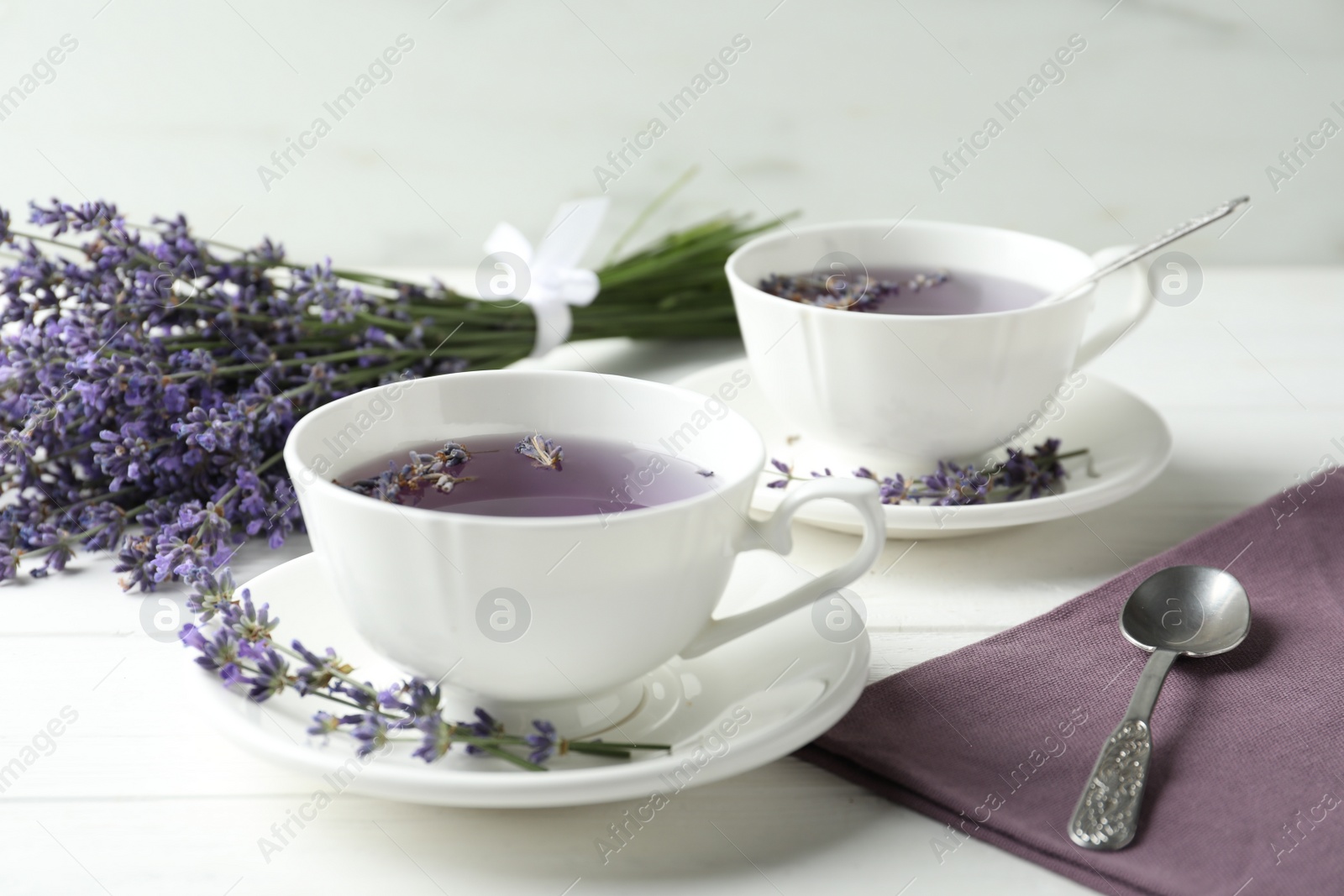 Photo of Fresh delicious tea with lavender and beautiful flowers on white wooden table