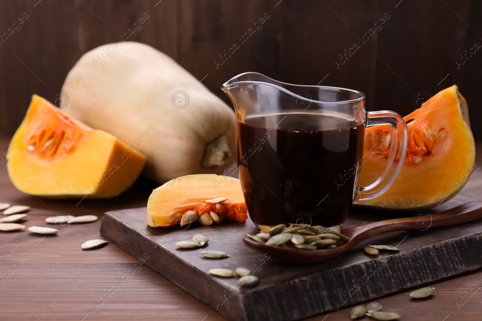 Photo of Fresh pumpkin seed oil in glass pitcher on wooden table