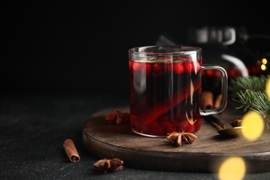 Photo of Tasty hot cranberry tea with rosemary, anise and cinnamon on black table. Space for text