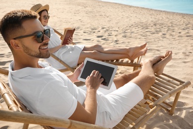 Photo of Young couple relaxing in deck chairs on sandy beach