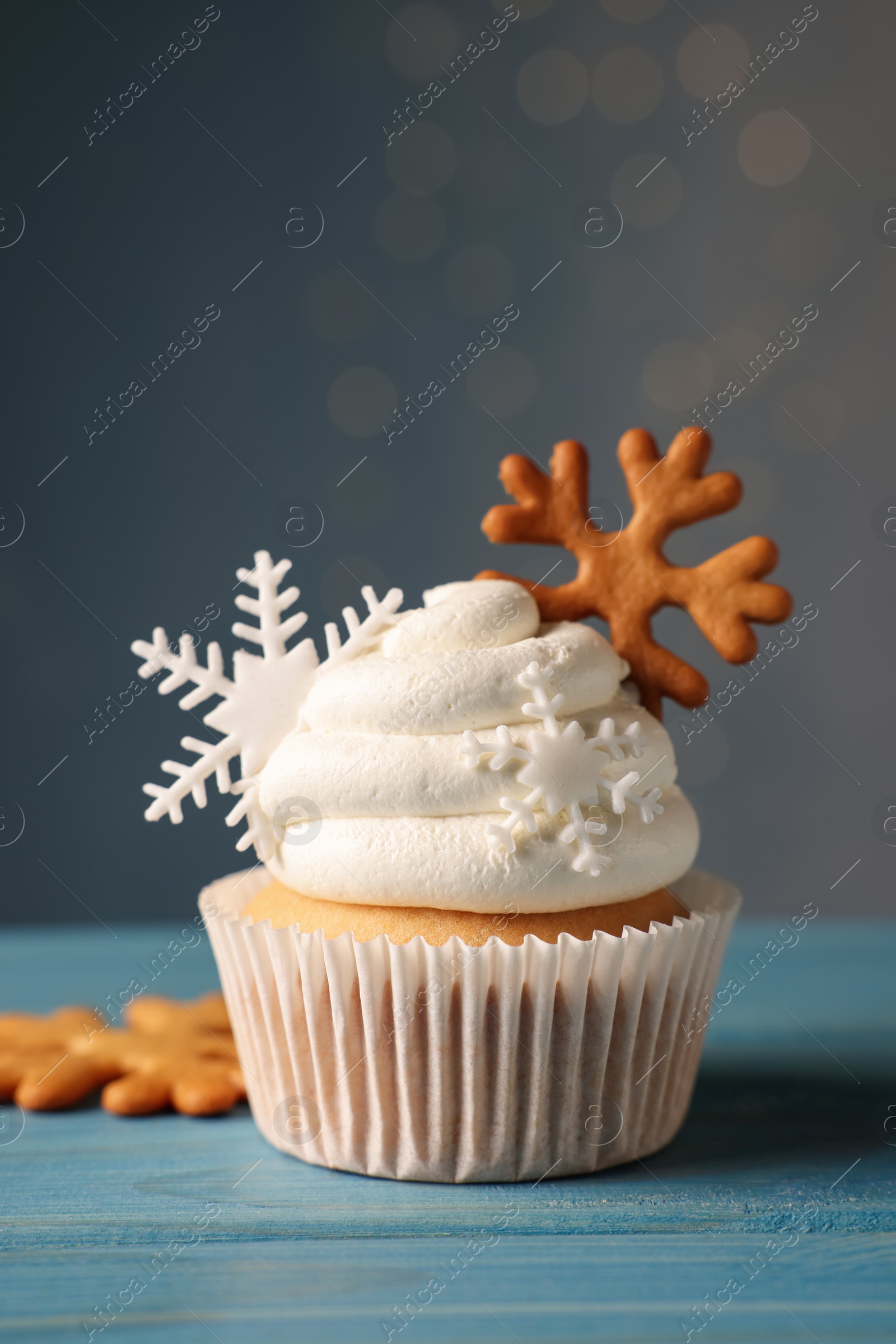 Photo of Tasty Christmas cupcake with snowflakes on light blue wooden table