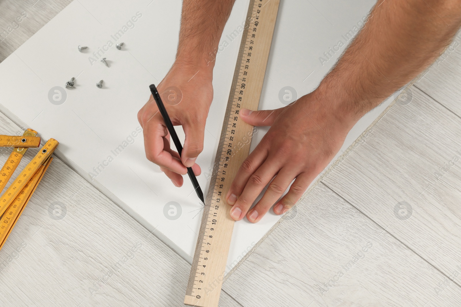 Photo of Man making mark on white board indoors, closeup. Furniture assembly