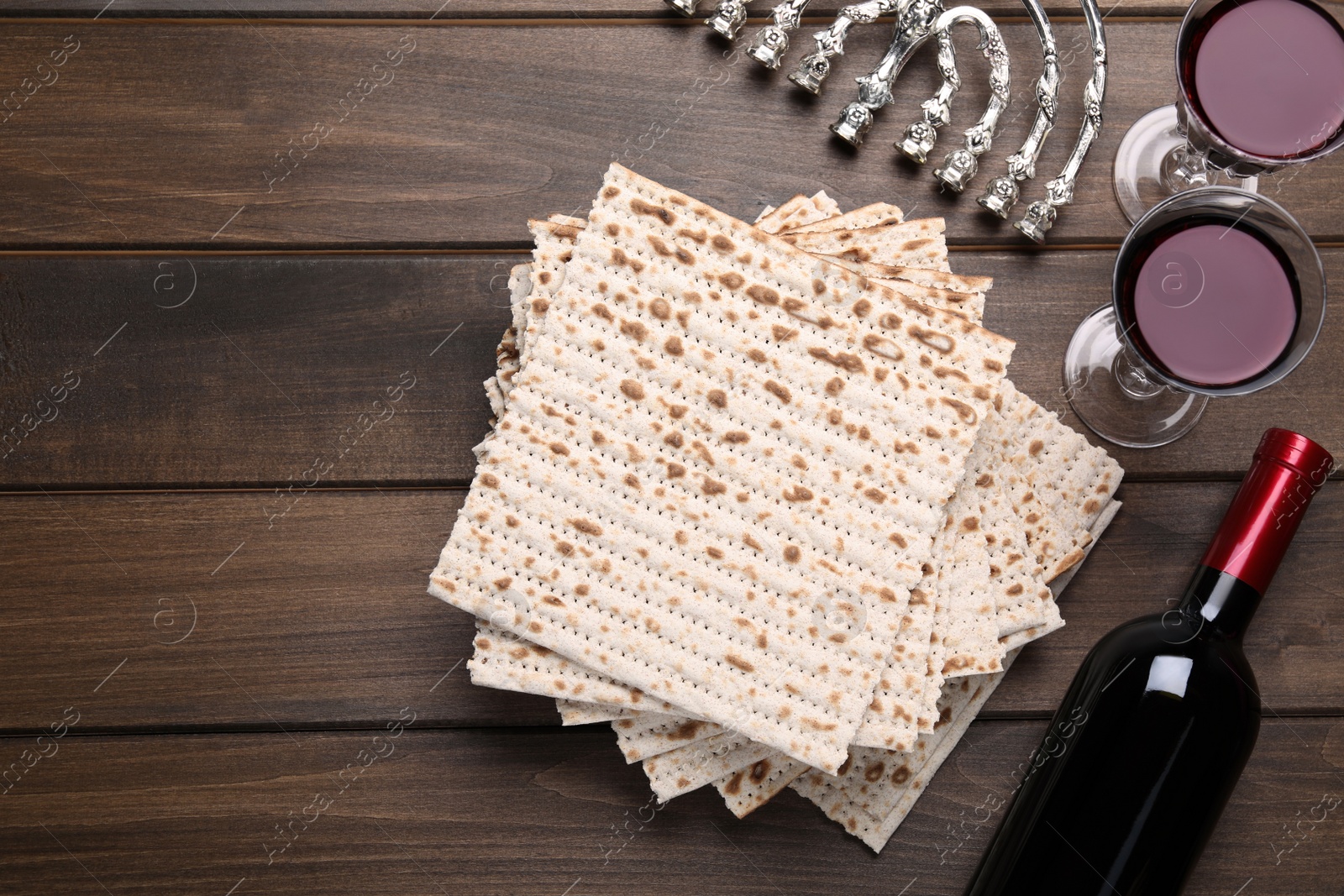 Photo of Matzos, red wine and menorah on wooden table, flat lay