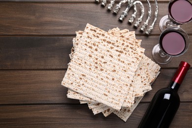 Photo of Matzos, red wine and menorah on wooden table, flat lay