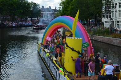 Photo of AMSTERDAM, NETHERLANDS - AUGUST 06, 2022: Many people in boat at LGBT pride parade on river