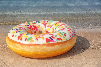 Photo of Bright inflatable doughnut ring near sea on sunny day