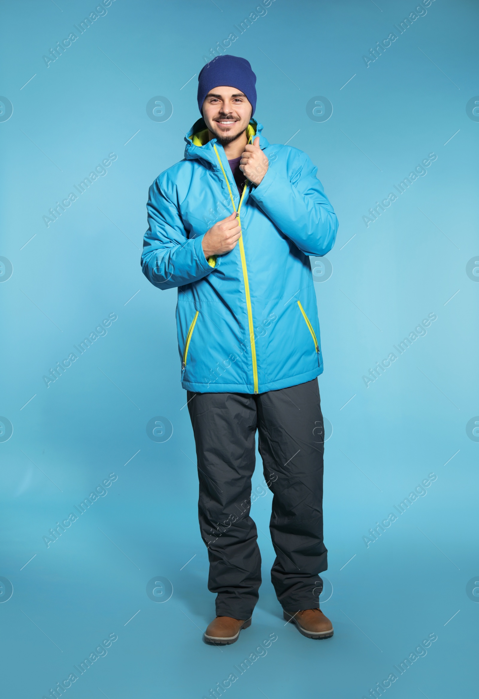 Photo of Young man wearing warm clothes on color background. Ready for winter vacation