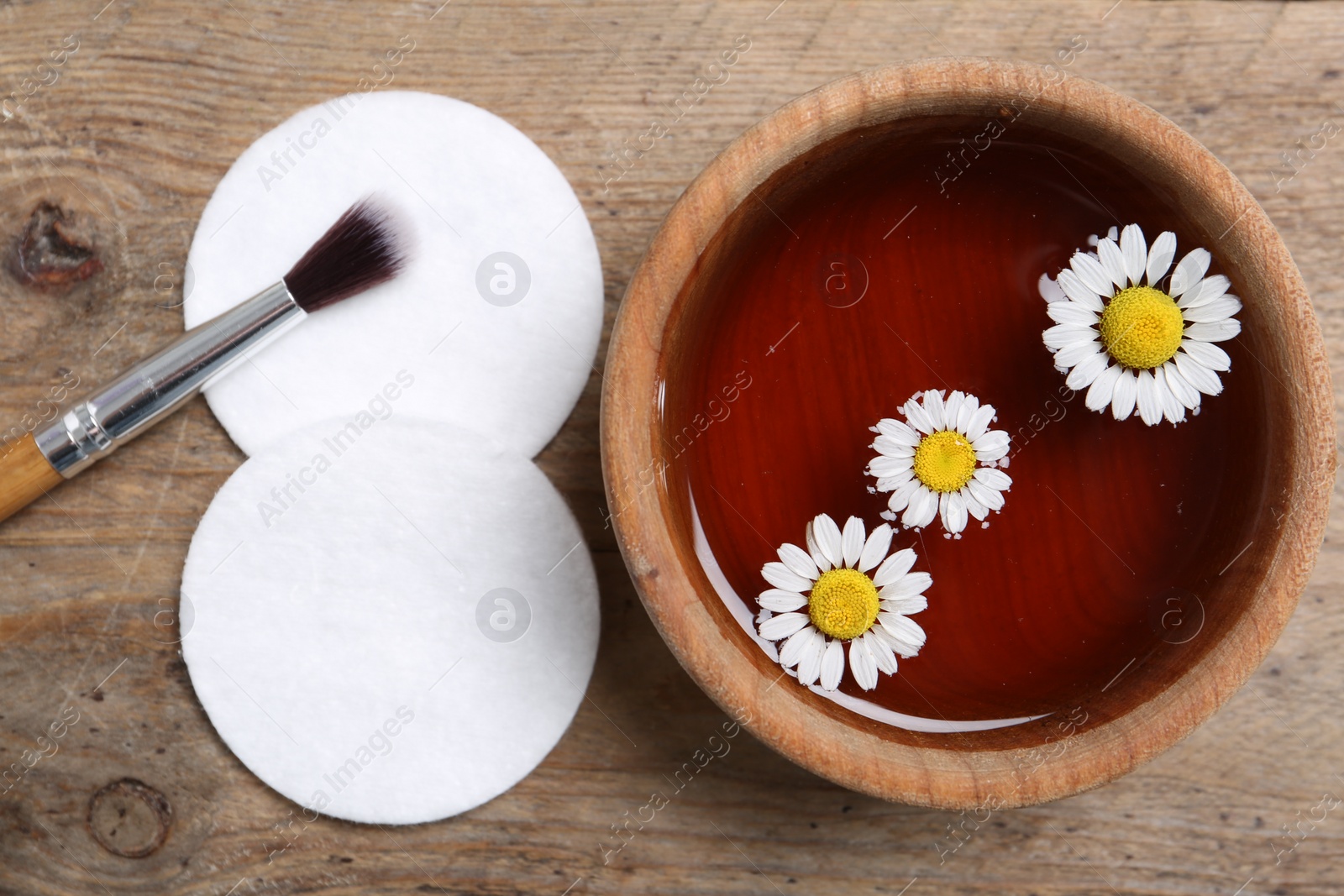 Photo of Flat lay composition with chamomile flowers and herbal infusion on wooden table