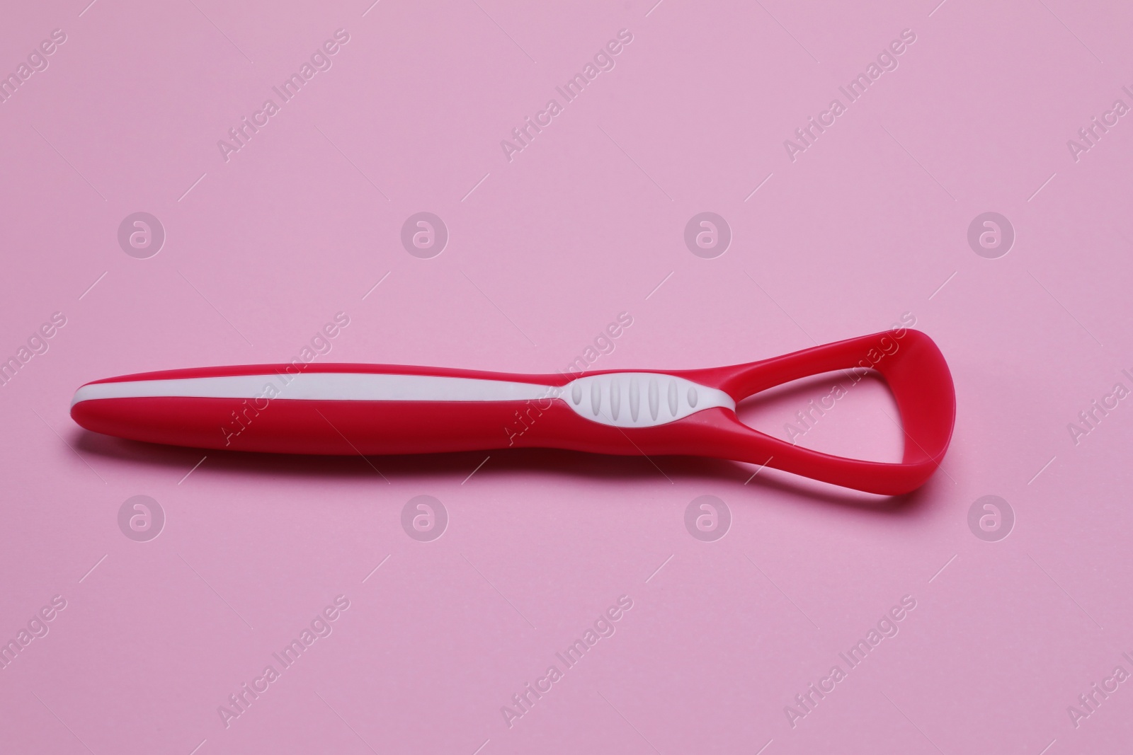 Photo of One red tongue cleaner on pink background