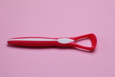 Photo of One red tongue cleaner on pink background