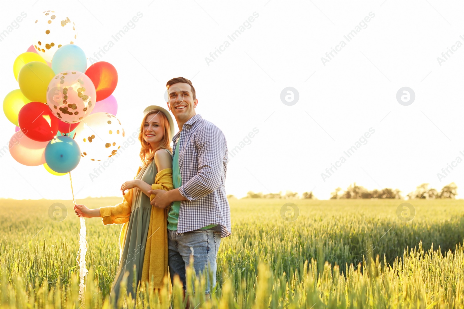 Photo of Young couple with colorful balloons outdoors on sunny day