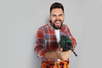Photo of Emotional man with power drill on grey background