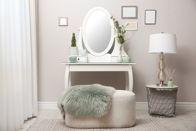 Photo of White dressing table with decor near beige wall in room