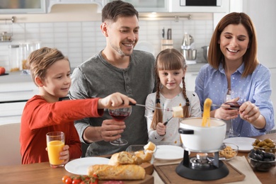 Happy family enjoying fondue dinner at home