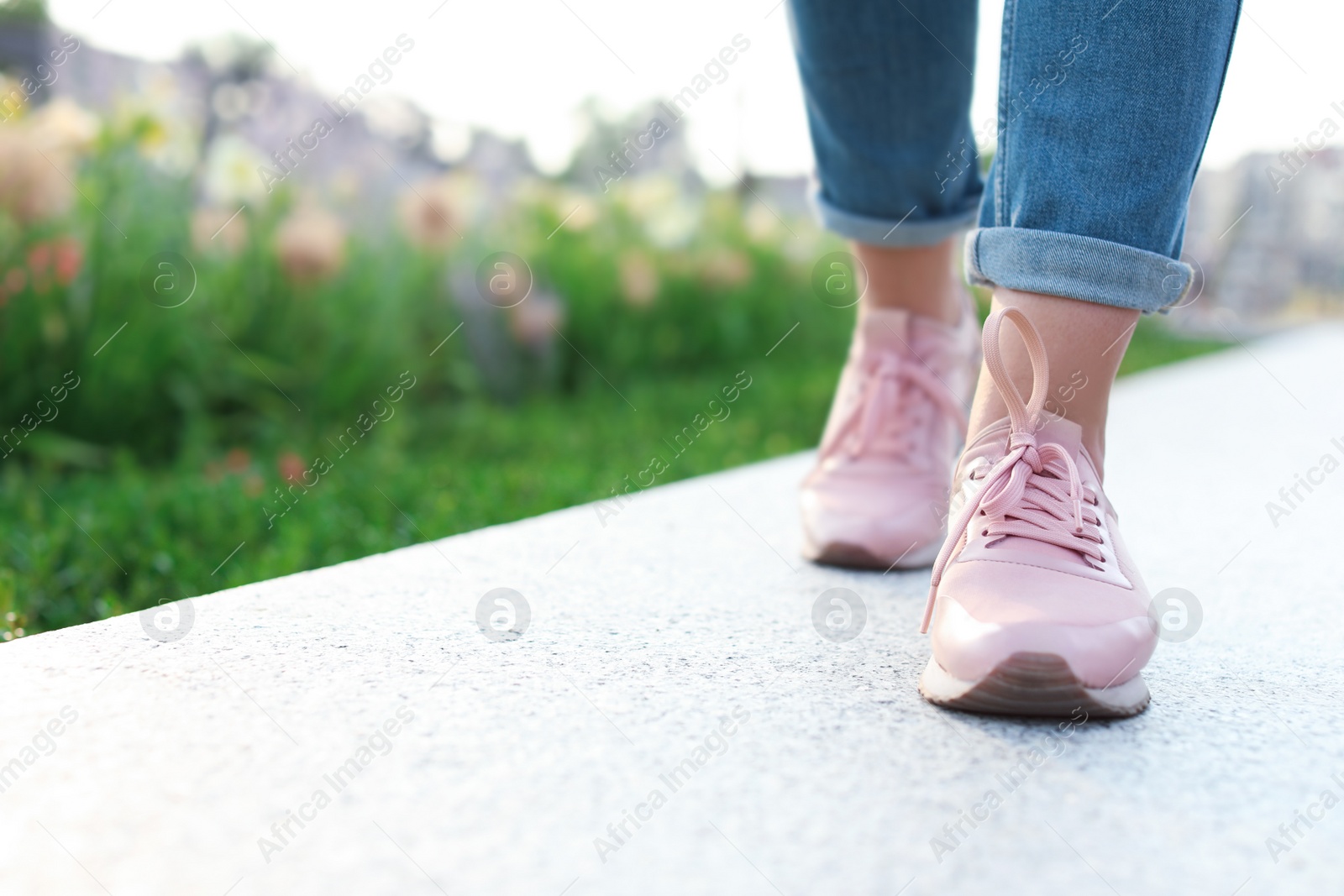 Photo of Woman in stylish sneakers walking outdoors, closeup. Urban fashion