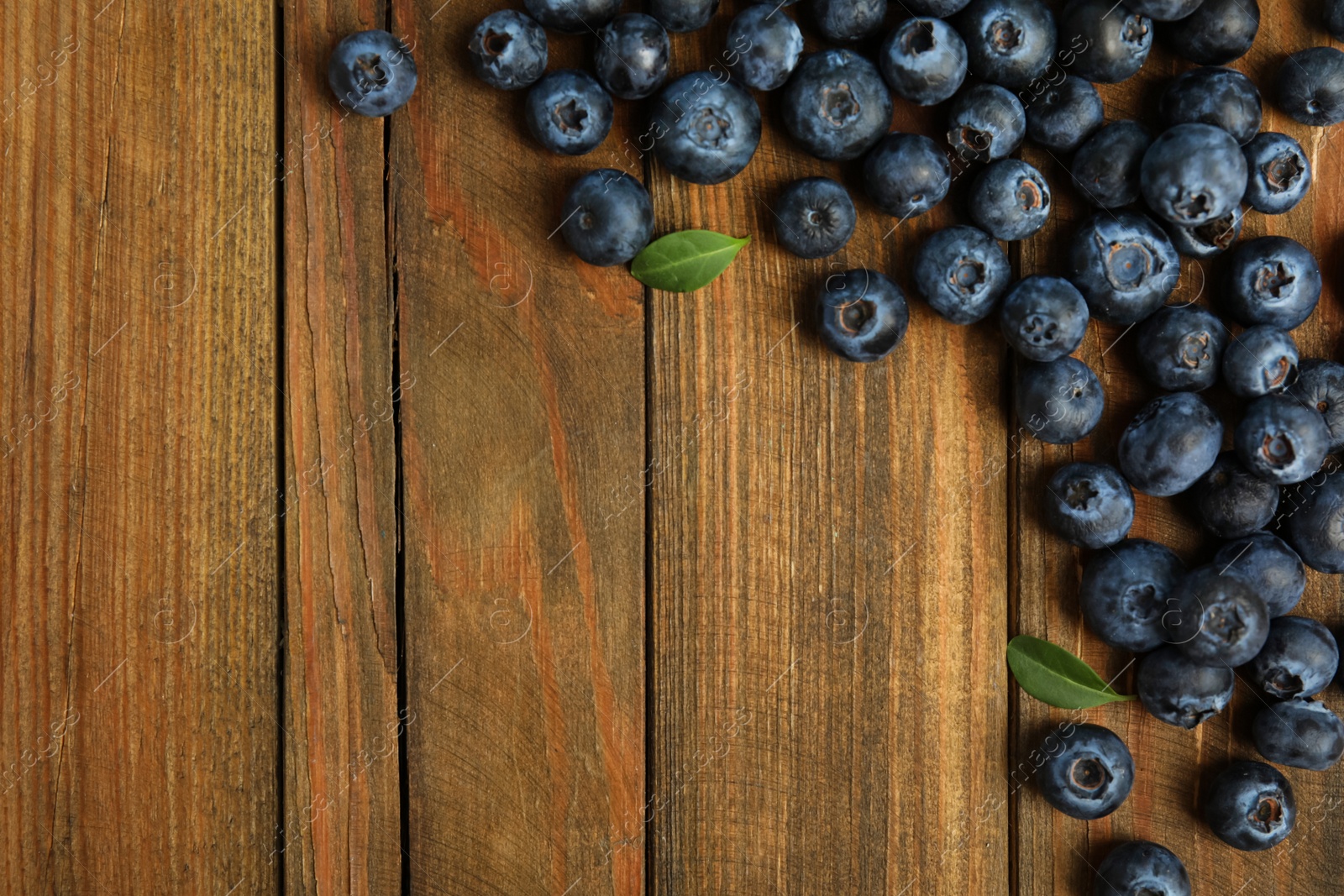 Photo of Fresh ripe blueberries on wooden table, flat lay. Space for text