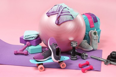 Many different sports equipment on pink background