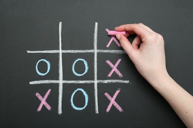 Photo of Woman playing tic tac toe on chalkboard, closeup