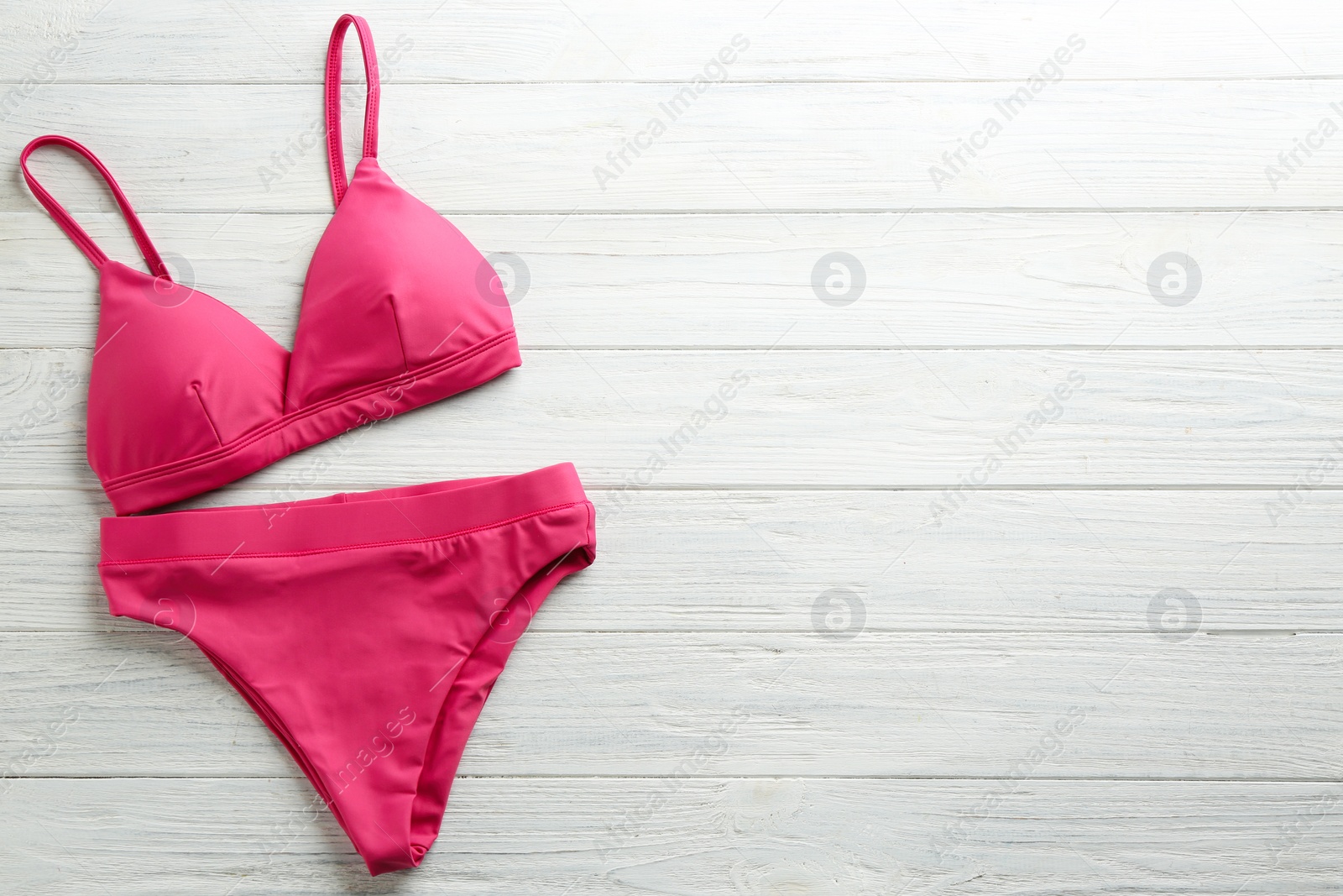 Photo of Beautiful pink bikini on white wooden background, top view. Space for text