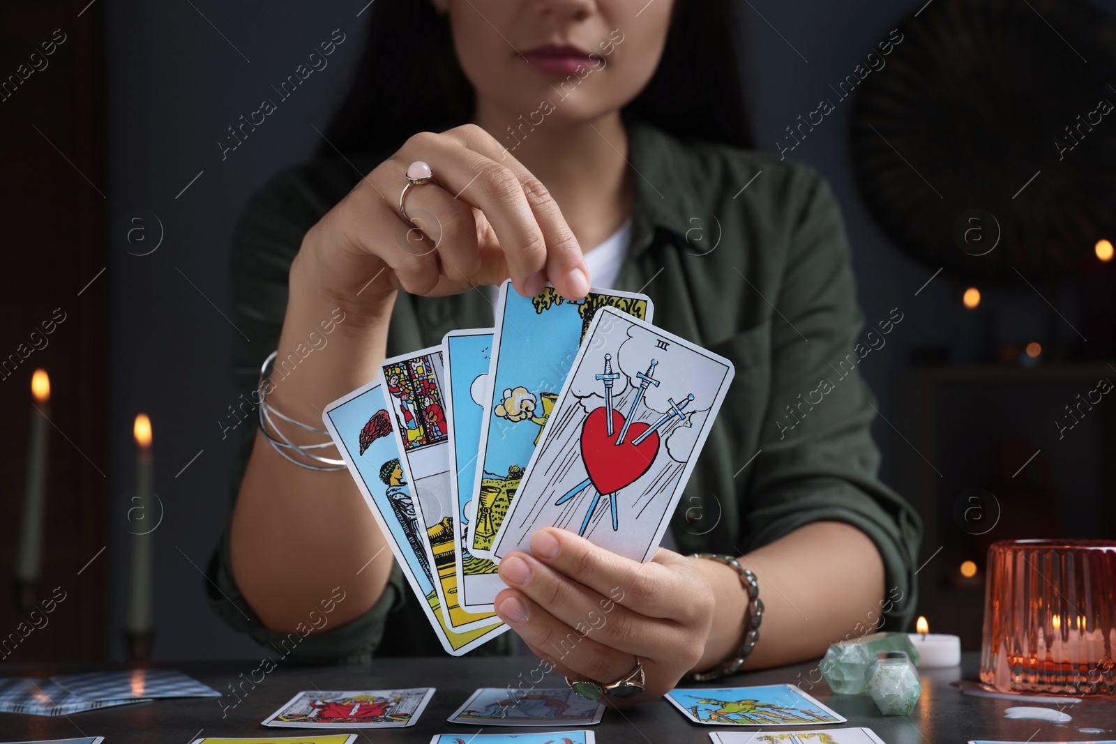 Photo of Fortune teller with tarot cards at grey table indoors, closeup