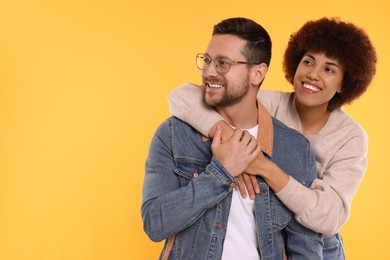 Photo of International dating. Happy couple hugging on orange background, space for text