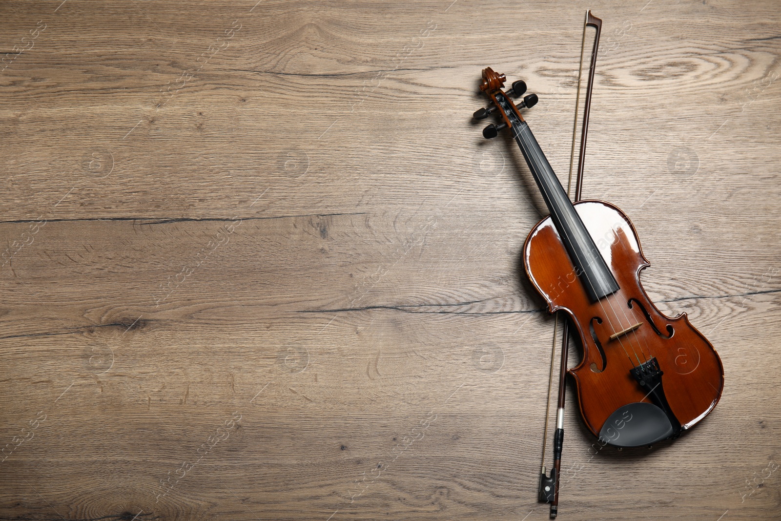 Photo of Classic violin and bow on wooden background, top view. Space for text