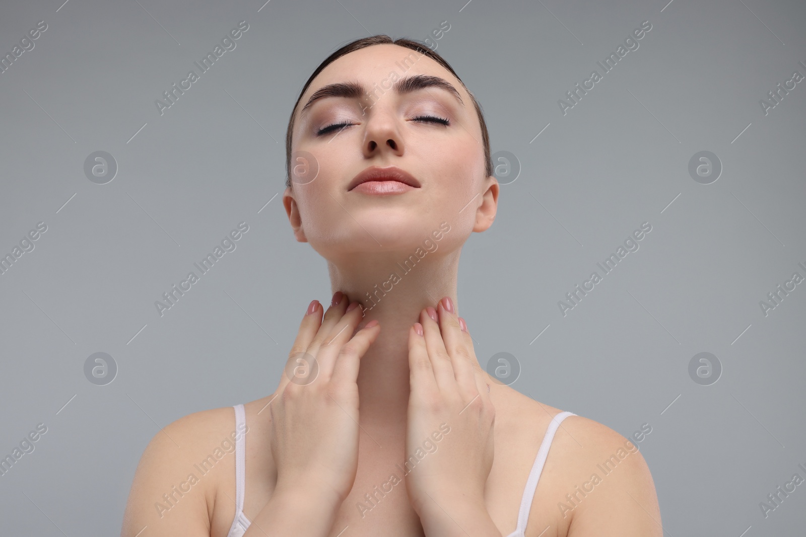 Photo of Beautiful woman touching her neck on grey background