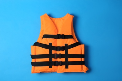 Orange life jacket on blue background. Personal flotation device