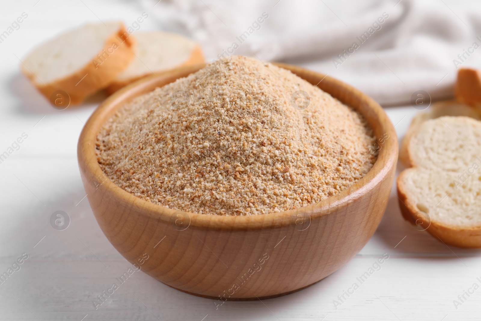 Photo of Fresh breadcrumbs in bowl on white wooden table