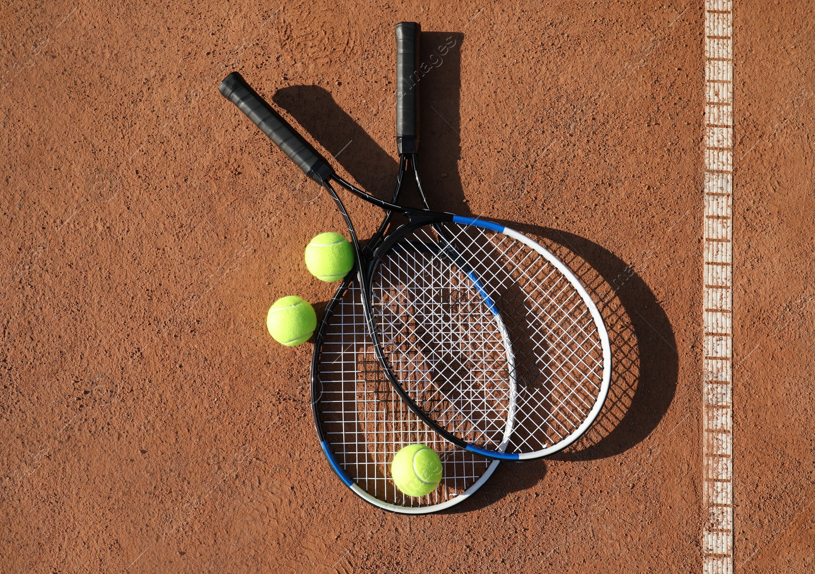 Photo of Tennis balls and rackets on clay court, flat lay