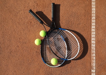 Photo of Tennis balls and rackets on clay court, flat lay