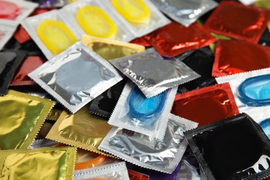 Pile of different condoms as background, closeup