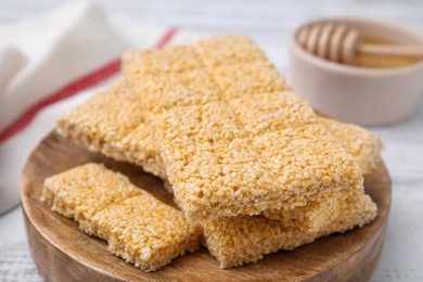 Photo of Wooden board with tasty sesame kozinaki bars on white table, closeup