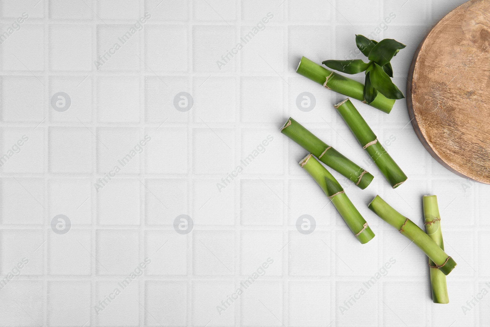 Photo of Pieces of beautiful green bamboo stems on white tiled table, flat lay. Space for text