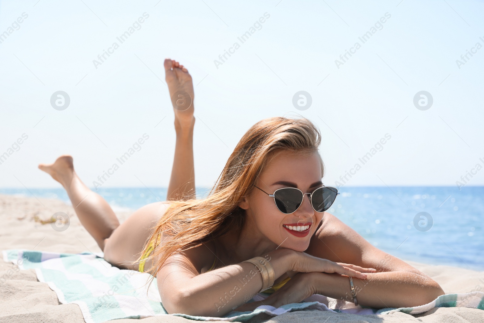 Photo of Beautiful woman with beach towel on sand near sea