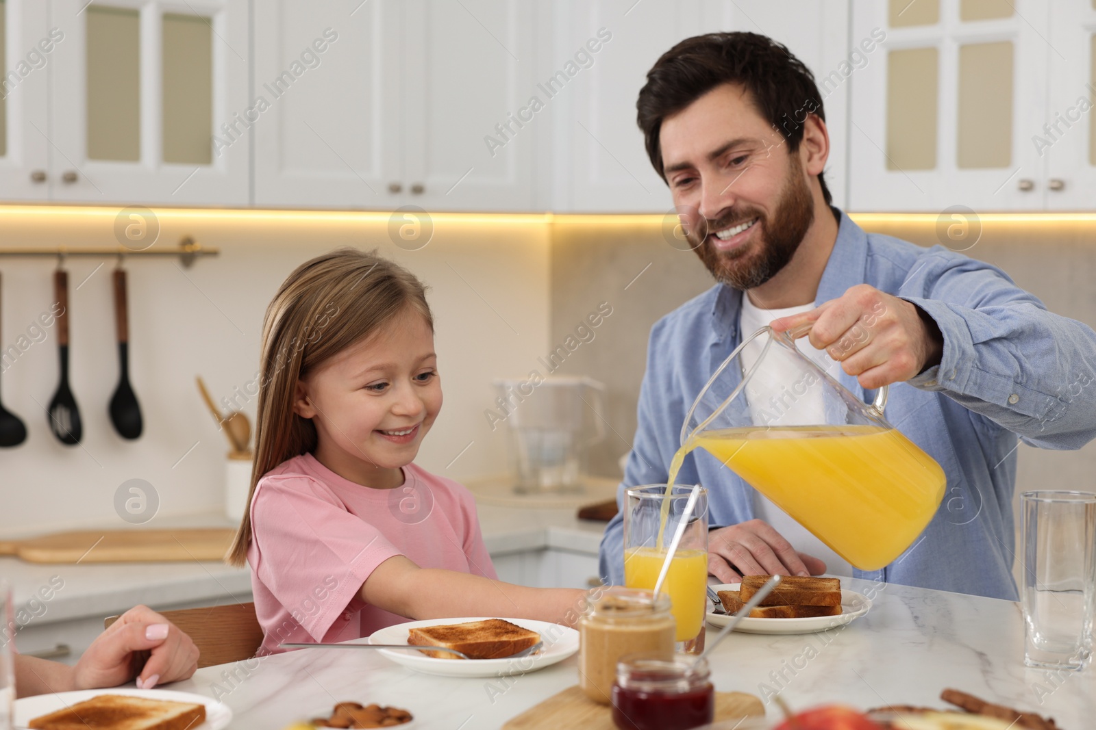 Photo of Happy family having breakfast at table in kitchen