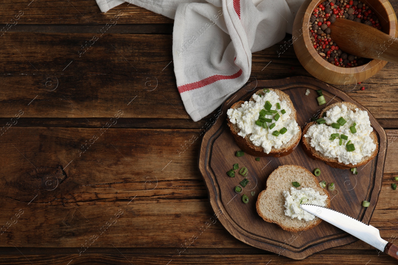 Photo of Bread with cottage cheese and green onion on wooden table, flat lay. Space for text