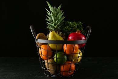 Photo of Fresh ripe fruits in metal basket on black table