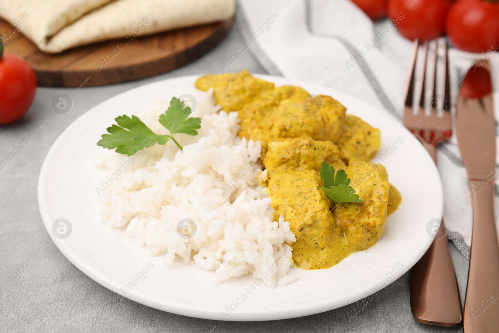 Photo of Delicious rice and chicken with curry sauce on light grey table, closeup