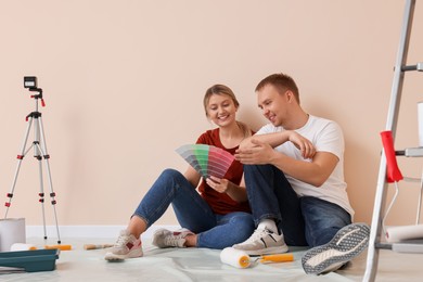 Photo of Couple with paint chips discussing new wall color in apartment during repair, space for text