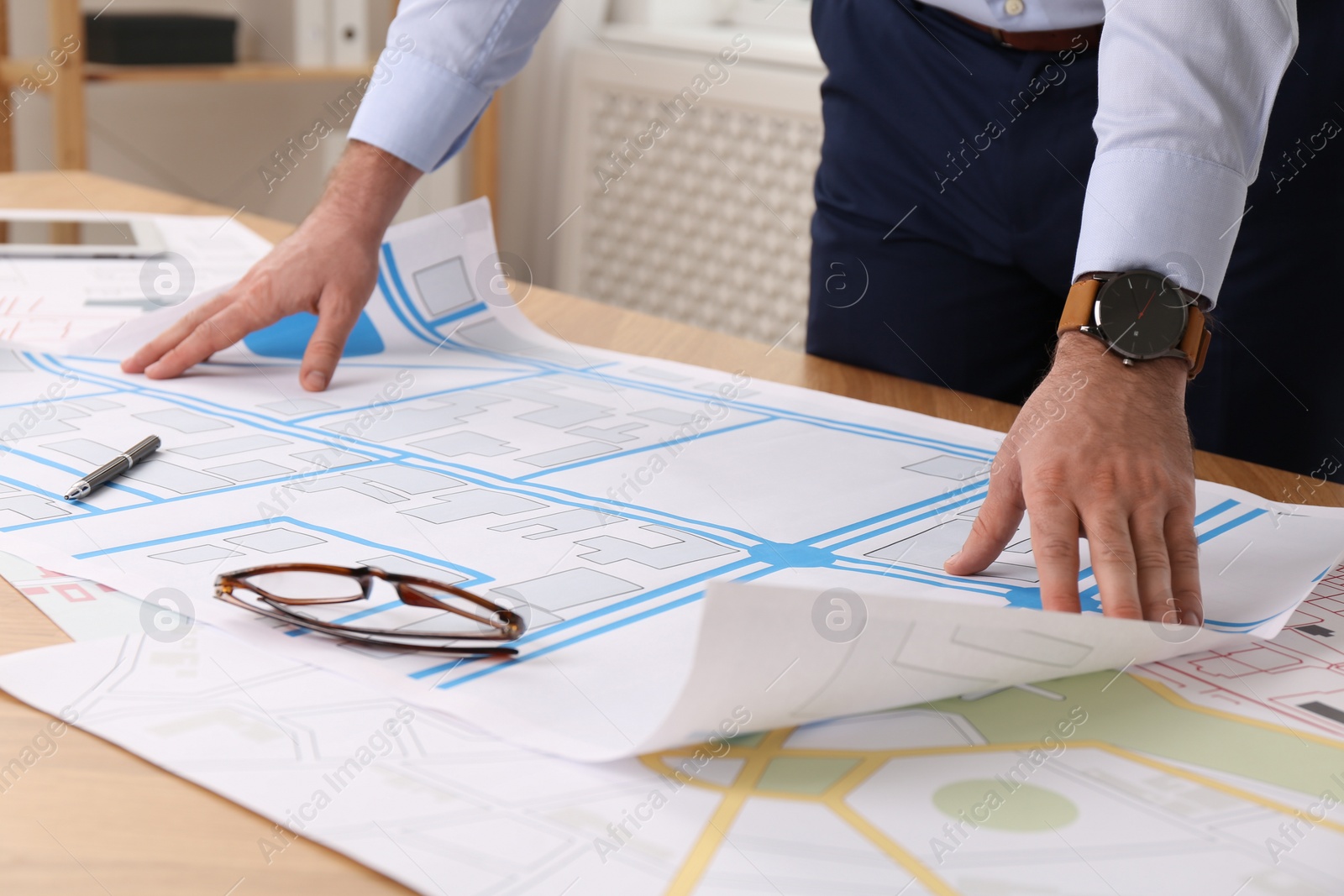 Photo of Professional cartographer working with cadastral map at table in office, closeup