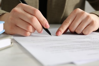 Photo of Woman signing document at wooden table, closeup