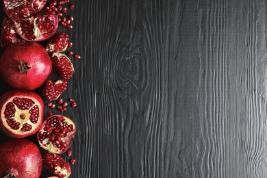 Photo of Ripe pomegranates on dark wooden background, top view with space for text