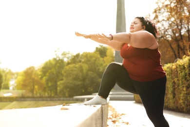 Beautiful overweight woman doing sport exercises in park