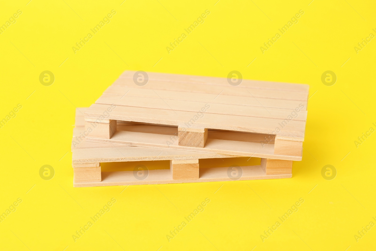 Photo of Two small wooden pallets on yellow background